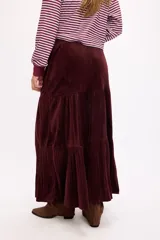 Falda larga de color negro con textura símil terciopelo, presenta un diseño con volados y detalle de tachas en la cintura.