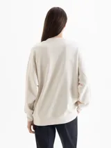 Buzo oversize de cuello redondo y manga larga, color crema. Presenta una estampa frontal con motivos florales, corazones y la frase 'A love letter to winter flowers'.