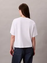 Remera blanca de manga corta Calvin Klein, con cuello redondo, corte regular y logo de la marca bordado en 3D en color fucsia en el pecho.