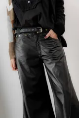 Pantalón de cuero ovino italiano de tiro medio y corte ancho. Presenta costuras diagonales en las piernas que aportan volumen y vuelo, con pretina y pasacintos confeccionados en gamuza al tono.