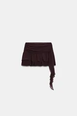 Falda pantalón de tiro medio en color bordó, con diseño de volantes y detalle asimétrico lateral. Cuenta con cierre lateral mediante cremallera oculta.