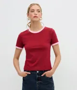 Blusa tipo baby tee de corte ajustado, color bordó con detalles en rosado contrastante en el cuello redondo y en los bordes de las mangas cortas.