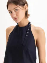 Top Lucille de silueta evasé, calce holgado y corte cropped, confeccionado en poplín Milano de algodón Pima. Cuenta con escote halter de sisa profunda, bretel regulable con ojalillos de níquel que envuelve el cuello, pinzas de entalle y espalda abierta.