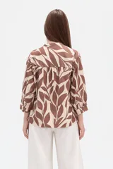Camisa de corte holgado con estampado animal print tipo cebra en tonos negro y beige. Presenta cuello mao, cierre frontal con botones y un bolsillo aplicado en el pecho.