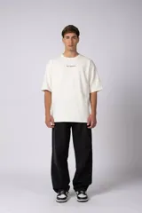 Remera oversize de algodón color beige, de manga corta y cuello redondo, con pequeño estampado frontal de la marca en tono bordó.