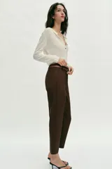 Pantalón tobillero de tiro medio, color azul marino, con bolsillos delanteros y cierre frontal con cremallera, botón y gancho. Incluye un cinturón fino de color marrón con hebilla metálica.