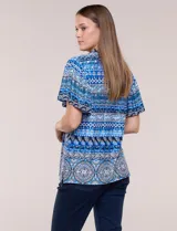 Blusa estampada en tonos azules con escote en V y cuello con frunces. Tiene mangas cortas amplias estilo mariposa y corte recto a la cadera.