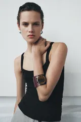 Maxi pulsera rígida de piel color bordó con una aplicación de piedra ojo de tigre incrustada en el centro, enmarcada por piezas metálicas doradas.