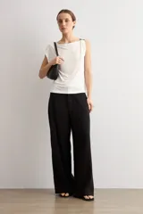 Blusa blanca de manga corta y corte recto, con escote bote y detalle metálico circular en el hombro.