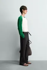 Camiseta de manga larga con diseño raglán, cuerpo color blanco crudo y mangas largas color verde esmeralda.