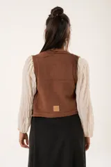 Chaleco color café de tejido sintético con escote en V y cierre frontal con botones forrados.