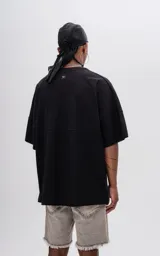 Remera negra de manga corta con calce extra oversize y recorte horizontal en el delantero y la espalda.