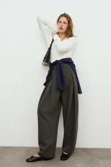 Pantalón balloon de tiro alto y diseño abuchonado, en color marrón oscuro con sutiles rayas verticales. Cuenta con pinzas y pliegues pronunciados en el delantero.