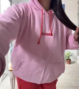 Canguro deportivo de tela suave con logo bordado, diseño holgado y mangas largas.