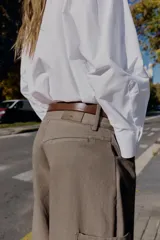 Pantalón cargo de tiro alto color marrón topo, con pierna ancha y holgada que se estrecha hacia el tobillo. Presenta bolsillos delanteros, bolsillo de plastrón lateral y falso bolsillo de vivo en la espalda.
