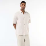 Camisa de manga corta en mezcla de lino, color crudo, con cuello camisero y cierre frontal de botones.