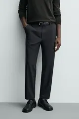 Pantalón de corte regular fit, color negro, confeccionado en tejido elástico. Presenta cintura elástica, cierre frontal con cremallera y botón, bolsillos laterales y bolsillos traseros de vivo.