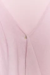 Top de punto rosado con escote en V y manga corta, decorado con un volante asimétrico en la parte delantera.