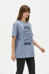 Remera de algodón negro con cuello redondo y diseño holgado, con estampado frontal de líneas horizontales blancas y un corazón rojo superpuesto.