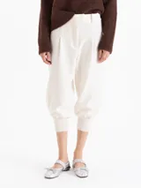 Pantalon negro de corte tipo babucha, con cintura estructurada, presillas para cinturón, bolsillos traseros y ruedos ajustados con puños tejidos.