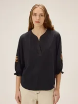 Remera de algodón de color negro con cuello en V y mangas tres cuartos abullonadas, con puños elásticos y detalles de bordado artesanal en las mangas.