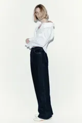Jean de tiro alto con corte wide leg, confeccionado en denim de algodón con leve stretch. Presenta diseño clásico de cinco bolsillos, cierre frontal con botón y costuras en contraste.