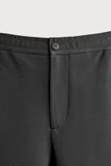 Pantalón negro confeccionado en mezcla de algodón, con cintura elástica, bolsillos frontales y cierre con cremallera y botón.