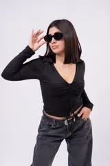 Crop top negro de manga larga con cuello solapa, escote en V y cordón ajustable con frunce frontal.