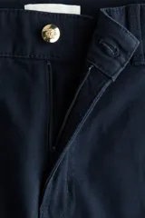 Pantalón acampanado de lona de algodón en color azul marino, con cintura de tiro alto, cierre de botón frontal y pliegues marcados en las piernas.