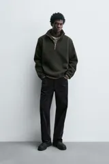 Sudadera de corte relajado confeccionada en tejido con textura. Presenta cuello subido con cierre frontal de cremallera metálica y manga larga.