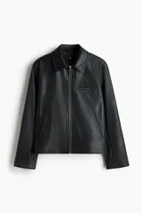 Campera de cuero sintético color negro con cuello camisero, cierre frontal, bolsillo superior con cierre y bolsillos laterales ribeteados.
