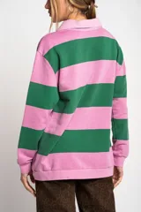 Sweater tipo polo de manga larga con diseño de rayas horizontales anchas en color rosa y gris. Presenta cuello camisero con cierre frontal de botones y puños elásticos.