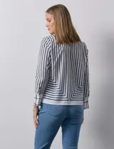 Blusa de gasa estampada con líneas verticales negras sobre fondo beige, de manga larga con puño abotonado. Espalda con abertura y botón.