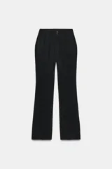Pantalón de tiro bajo negro, corte flare con bajo evasé, bolsillos delanteros y cierre frontal con cremallera y botones.