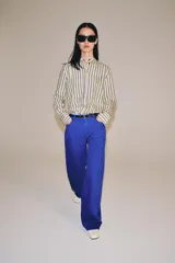 Jeans de tiro medio y corte barrel leg, de color azul, con diseño de cinco bolsillos y trabillas en la cintura. Cierre frontal con cremallera y botón metálico.