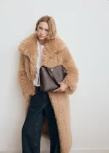 Bolso de hombro tipo hobo en color marrón oscuro, con diseño estructurado, cierre de botón a presión y detalle metálico frontal.