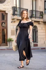 Vestido midi de color negro, con escote cuadrado, mangas cortas abullonadas y detalle de frunces con lazo en el centro del pecho. Presenta una silueta entallada en la cintura y falda con caída fluida.