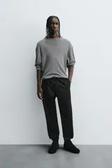 Pantalón tipo jogger de corte slim fit, confeccionado en tejido de algodón con elasticidad. Presenta cintura elástica ajustable con cordón, bolsillos frontales, bolsillos traseros de vivo y bajos con puños elásticos.