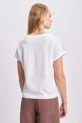 Remera blanca de manga corta con detalle de puntilla en el cuello y las mangas.