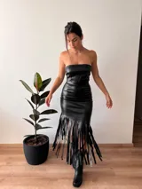 Falda midi negra de cuero sintético, corte ajustado y flecos largos en el ruedo.