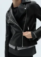 Chaqueta de diseño biker en efecto piel color negro, con solapas con muesca, cierre cruzado con cremallera y bolsillos laterales con cremallera.