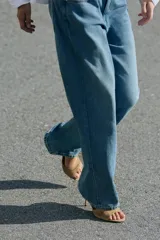 Sandalia de tacón destalonada estilo mule en piel, de color beige, con tira ancha delantera y tacón alto fino.