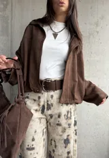 Campera tipo bomber de gamuza color chocolate, con diseño oversize, mangas amplias y apliques decorativos en los hombros. Cuenta con cierre frontal y forro interior.