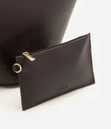Cartera shopper de diseño estructurado en forma de trapecio invertido, color marrón oscuro, con asas de hombro y detalles metálicos dorados.