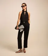Pantalón de corte recto para mujer, confeccionado en jacquard negro con textura. Cuenta con cintura elástica integrada, hebilla decorativa frontal y cierre lateral.