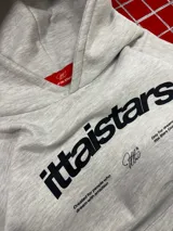 Hoodie gris jaspeado con capucha, bolsillo frontal tipo canguro y estampado gráfico en el pecho con la marca ittaistars.