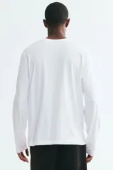 Remera blanca de manga larga en punto de algodón liviano, con cuello redondo ribeteado y corte estándar.