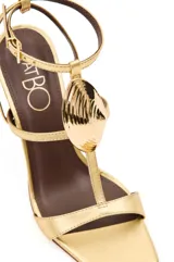 Sandalias de tacón alto PatBo modelo Zulu, color dorado metalizado, con tira en la puntera, diseño en T con aplique rígido en forma de concha marina, correa ajustable al tobillo y plantilla marrón.