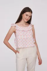 Blusa de algodón con estampado geométrico en tonos rosado y blanco, diseño holgado con escote bote y detalle de volados en los hombros.