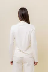 Polera de manga larga en color crudo, confeccionada en tejido suave y liviano con leve elasticidad. Presenta un cuello alto tipo tortuga y un calce regular, ideal para usar como prenda base o sola.